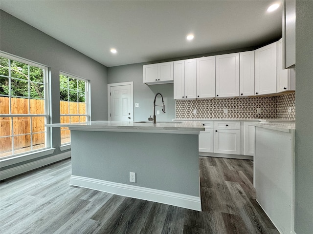 kitchen with dark hardwood / wood-style flooring, backsplash, a kitchen island with sink, sink, and white cabinets