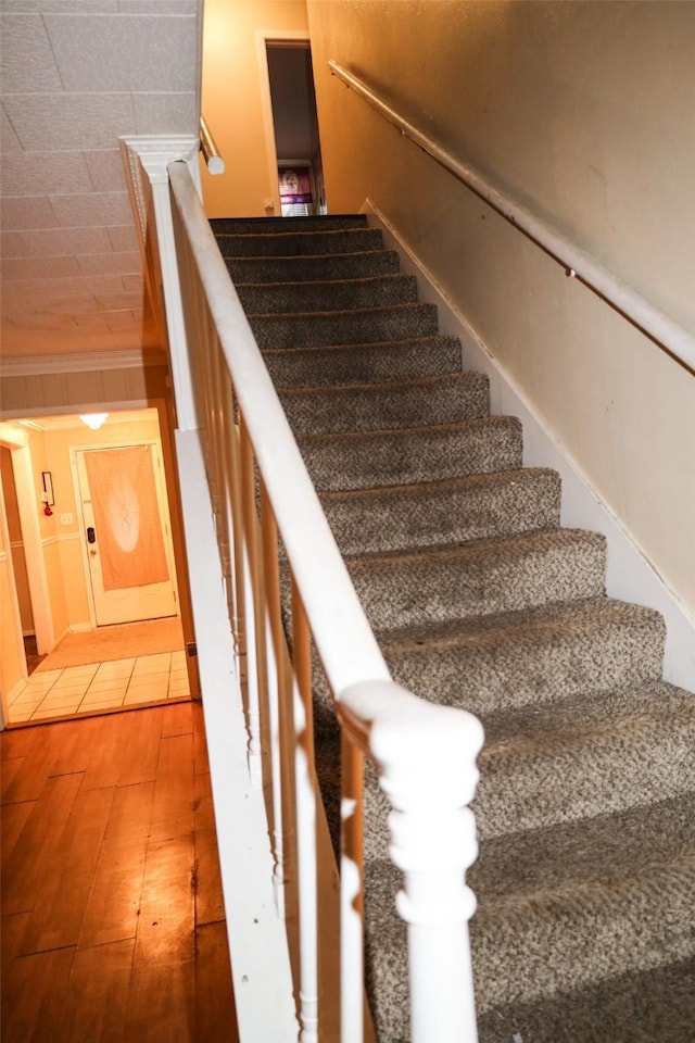 staircase with crown molding and hardwood / wood-style floors