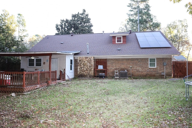 rear view of property with solar panels, a yard, a deck, and central air condition unit