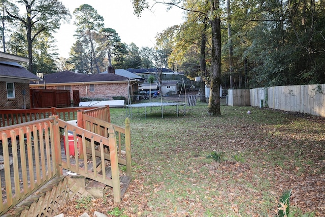 view of yard featuring a wooden deck and a trampoline