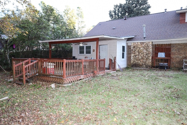 back of property with a wooden deck, ceiling fan, and a yard