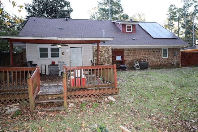 rear view of house with a lawn, ceiling fan, solar panels, central AC, and a wooden deck