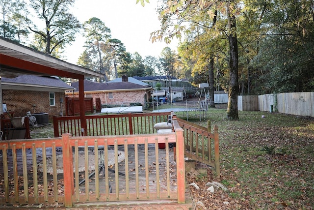 view of yard featuring a trampoline, central AC unit, and a wooden deck