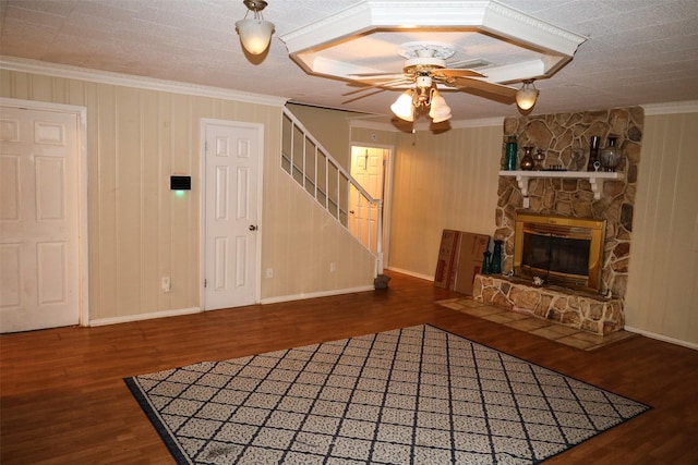 unfurnished living room with a stone fireplace, crown molding, and dark hardwood / wood-style flooring