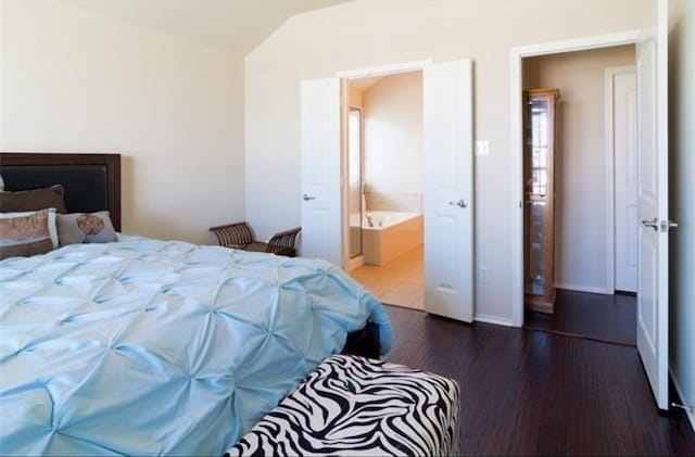 bedroom with dark hardwood / wood-style flooring, connected bathroom, and lofted ceiling