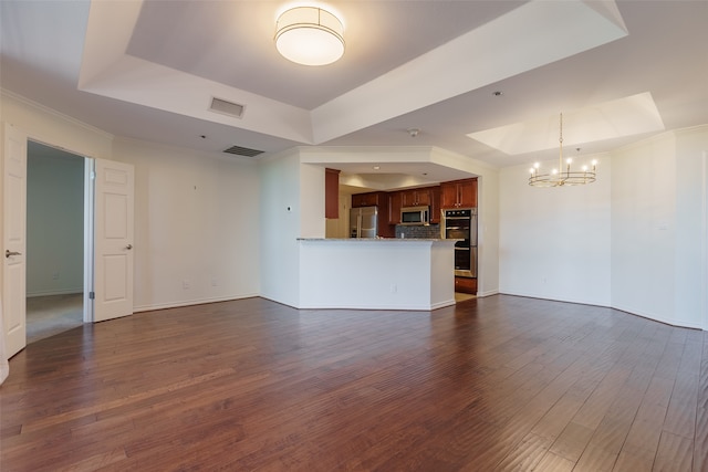 unfurnished living room with dark hardwood / wood-style floors, a raised ceiling, crown molding, and an inviting chandelier