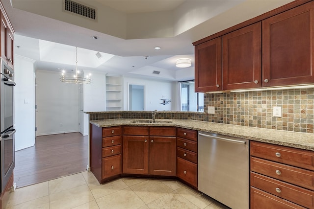 kitchen with light stone counters, appliances with stainless steel finishes, a raised ceiling, and sink