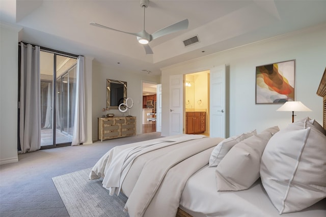 bedroom with access to exterior, ensuite bathroom, a tray ceiling, ornamental molding, and light carpet