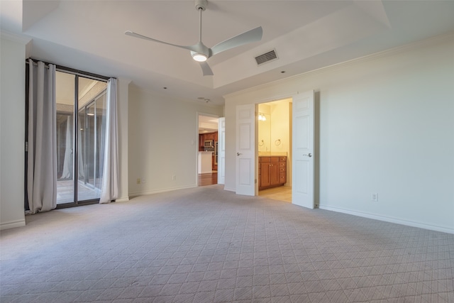 carpeted empty room with ceiling fan, a raised ceiling, and crown molding