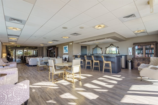 dining room featuring hardwood / wood-style flooring and a drop ceiling