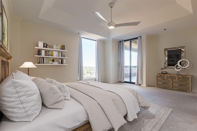 carpeted bedroom with ornamental molding, access to exterior, ceiling fan, and a tray ceiling