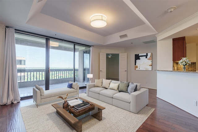 living room featuring a tray ceiling, expansive windows, and dark wood-type flooring