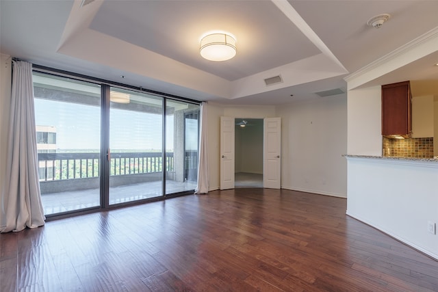 unfurnished room featuring dark hardwood / wood-style floors, a raised ceiling, and expansive windows