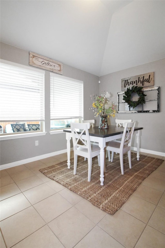 tiled dining space featuring lofted ceiling