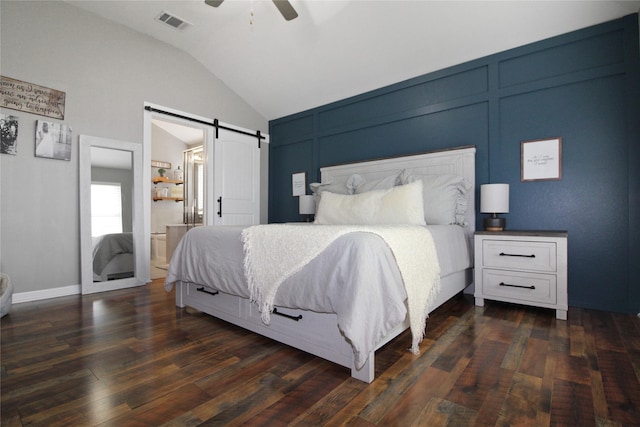 bedroom with ceiling fan, a barn door, connected bathroom, dark hardwood / wood-style floors, and lofted ceiling