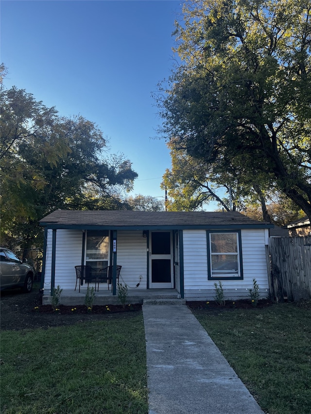 ranch-style home featuring covered porch and a front yard