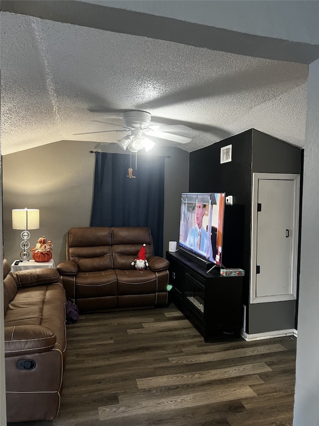 living room with ceiling fan, vaulted ceiling, a textured ceiling, and dark wood-type flooring