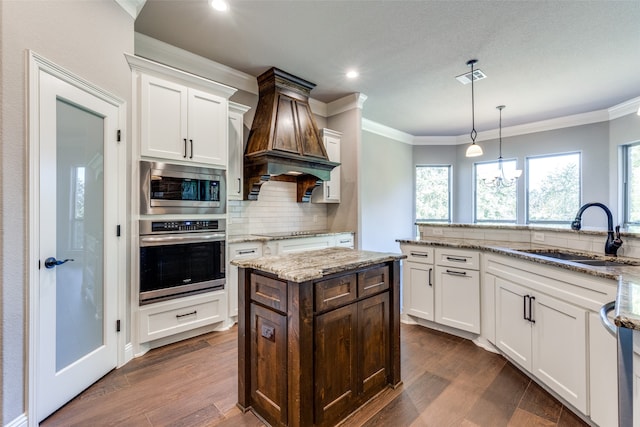 kitchen with white cabinetry, sink, hanging light fixtures, and appliances with stainless steel finishes