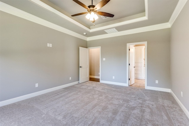 unfurnished bedroom featuring light carpet, a tray ceiling, crown molding, and ensuite bathroom