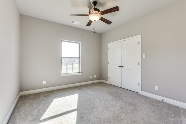 unfurnished bedroom with ceiling fan, a closet, and light carpet