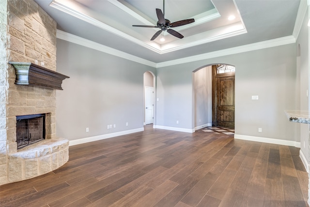 unfurnished living room featuring dark hardwood / wood-style floors, a fireplace, a raised ceiling, and ceiling fan