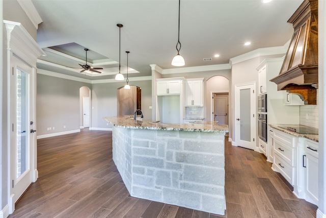 kitchen with appliances with stainless steel finishes, white cabinetry, a kitchen island with sink, decorative light fixtures, and custom exhaust hood