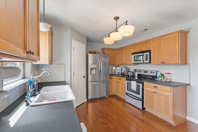 kitchen with backsplash, sink, dark hardwood / wood-style floors, appliances with stainless steel finishes, and decorative light fixtures