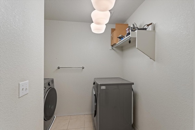 clothes washing area featuring washer and dryer and light tile patterned floors