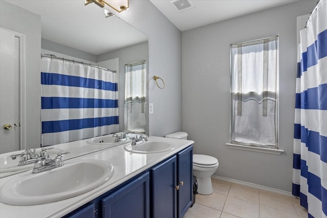 bathroom featuring toilet, plenty of natural light, vanity, and tile patterned flooring