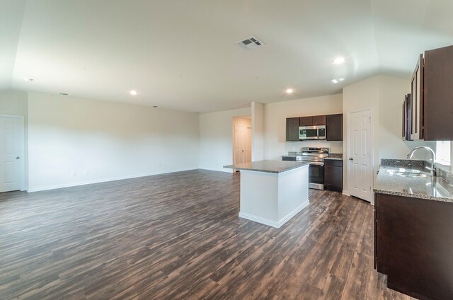 kitchen with dark brown cabinetry, sink, a center island, stainless steel appliances, and dark hardwood / wood-style floors