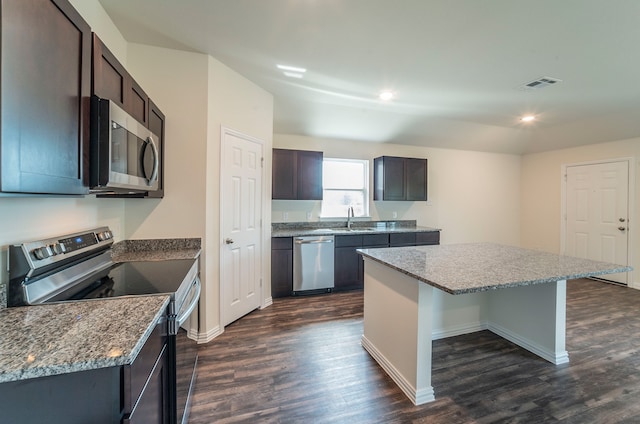 kitchen with dark brown cabinetry, a center island, sink, dark wood-type flooring, and stainless steel appliances