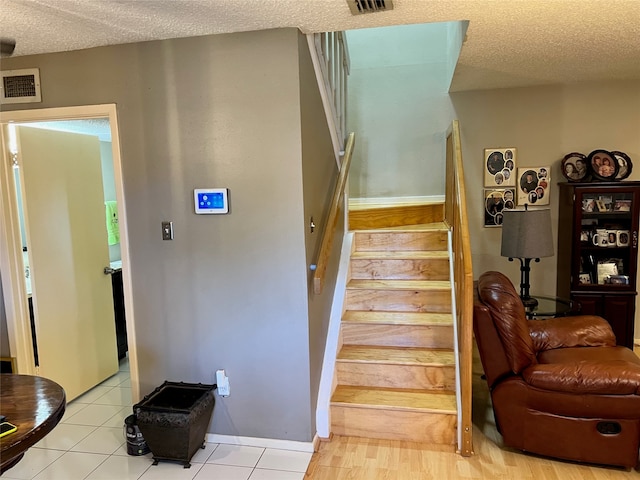 staircase with tile patterned flooring and a textured ceiling