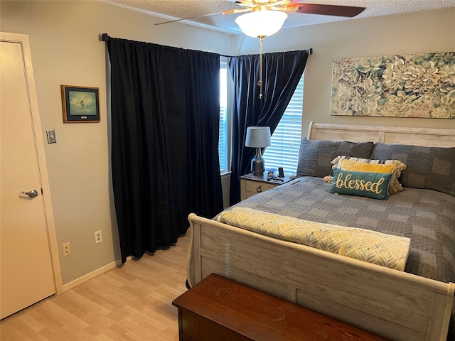 bedroom featuring ceiling fan, light hardwood / wood-style floors, and a textured ceiling