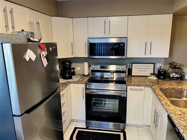 kitchen with stone counters, white cabinetry, stainless steel appliances, backsplash, and light tile patterned floors