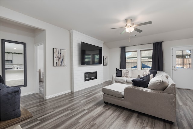 living room with hardwood / wood-style flooring, ceiling fan, and a large fireplace