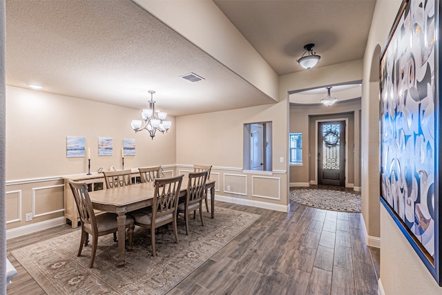 dining area with a chandelier, dark wood-type flooring, and a textured ceiling