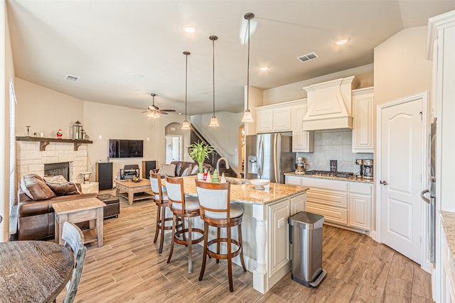 kitchen with light stone counters, light hardwood / wood-style flooring, stainless steel appliances, and custom exhaust hood