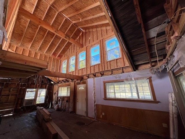 misc room featuring high vaulted ceiling and wooden walls