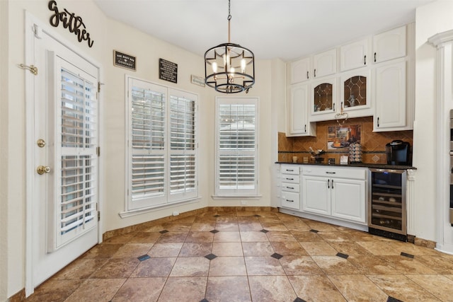 kitchen with hanging light fixtures, beverage cooler, an inviting chandelier, tasteful backsplash, and white cabinets