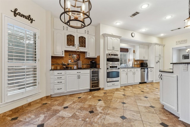 kitchen with white cabinetry, tasteful backsplash, wine cooler, pendant lighting, and appliances with stainless steel finishes