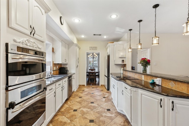 kitchen featuring white cabinetry, sink, hanging light fixtures, stainless steel appliances, and dark stone counters