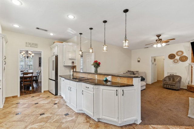 kitchen with stainless steel fridge, ceiling fan with notable chandelier, light colored carpet, pendant lighting, and white cabinets