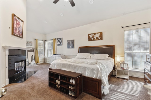 carpeted bedroom featuring multiple windows, ceiling fan, and a fireplace