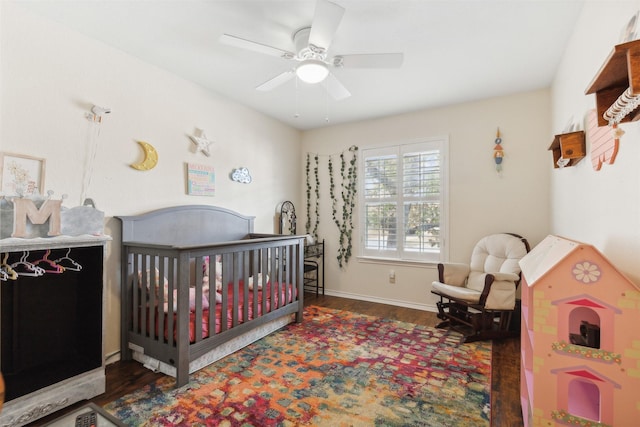 bedroom featuring ceiling fan, dark wood-type flooring, and a crib