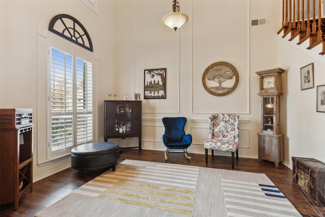 living area featuring a towering ceiling and dark wood-type flooring