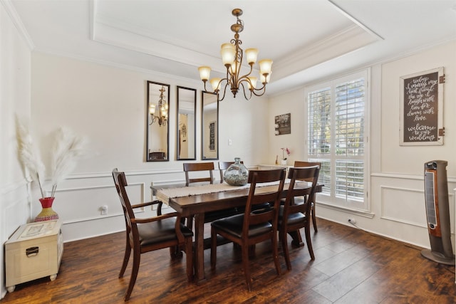 dining area featuring dark hardwood / wood-style floors, a raised ceiling, ornamental molding, and a chandelier