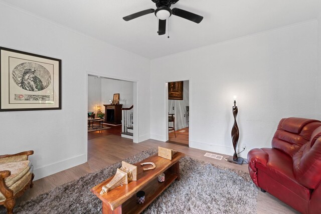 living room with hardwood / wood-style floors, ceiling fan, and crown molding