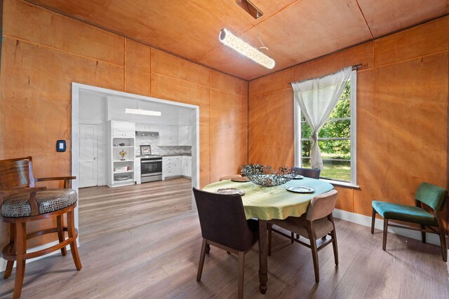 dining room with wood-type flooring and wooden walls