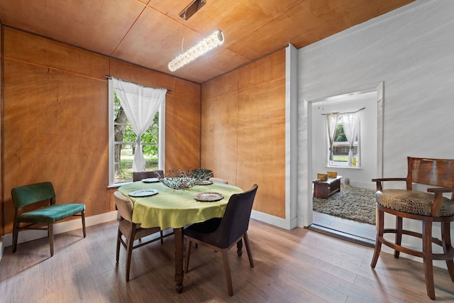 dining room featuring hardwood / wood-style flooring, wood walls, and wooden ceiling