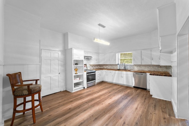 kitchen with white cabinets, sink, appliances with stainless steel finishes, decorative light fixtures, and dark hardwood / wood-style flooring